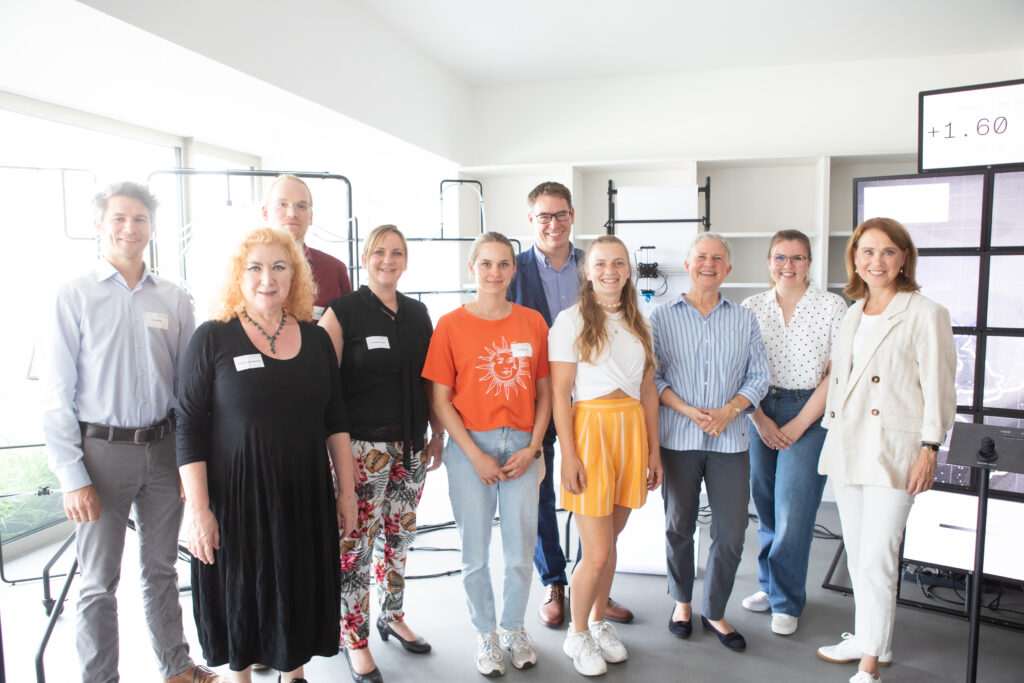 The image shows various representatives of scicom-initiatives in Tübingen inside the showroom. Minister Olschowski is standing on the right. 