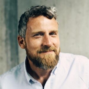 Portraitfoto von Christoph Koch in hellem Hemd vor grauem Hintergrund