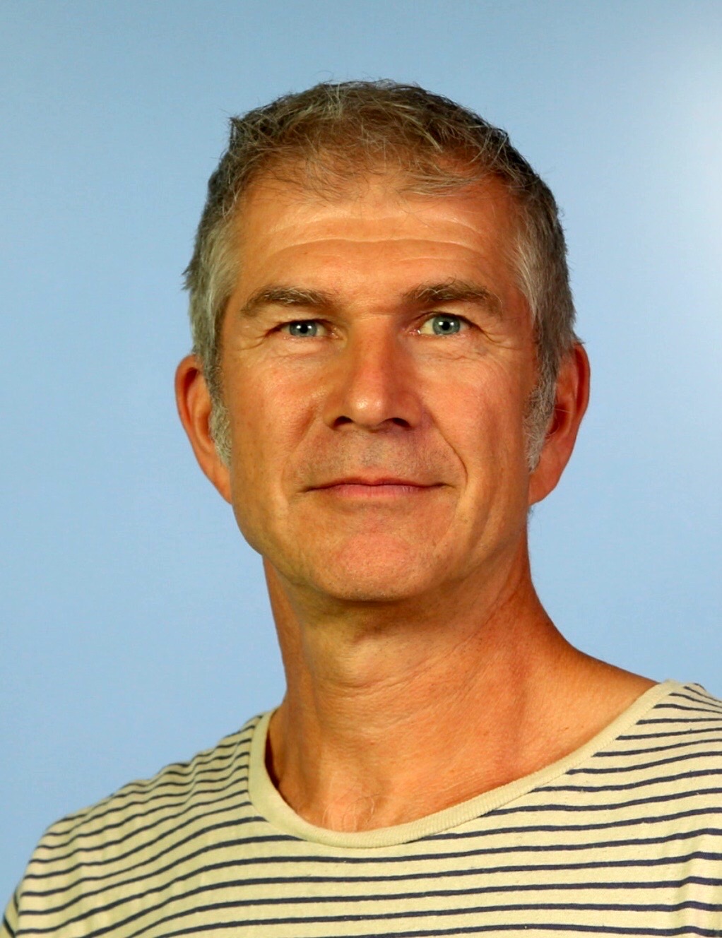 Porträtfoto von Oliver Häußler vor hellblauem Hintergrund